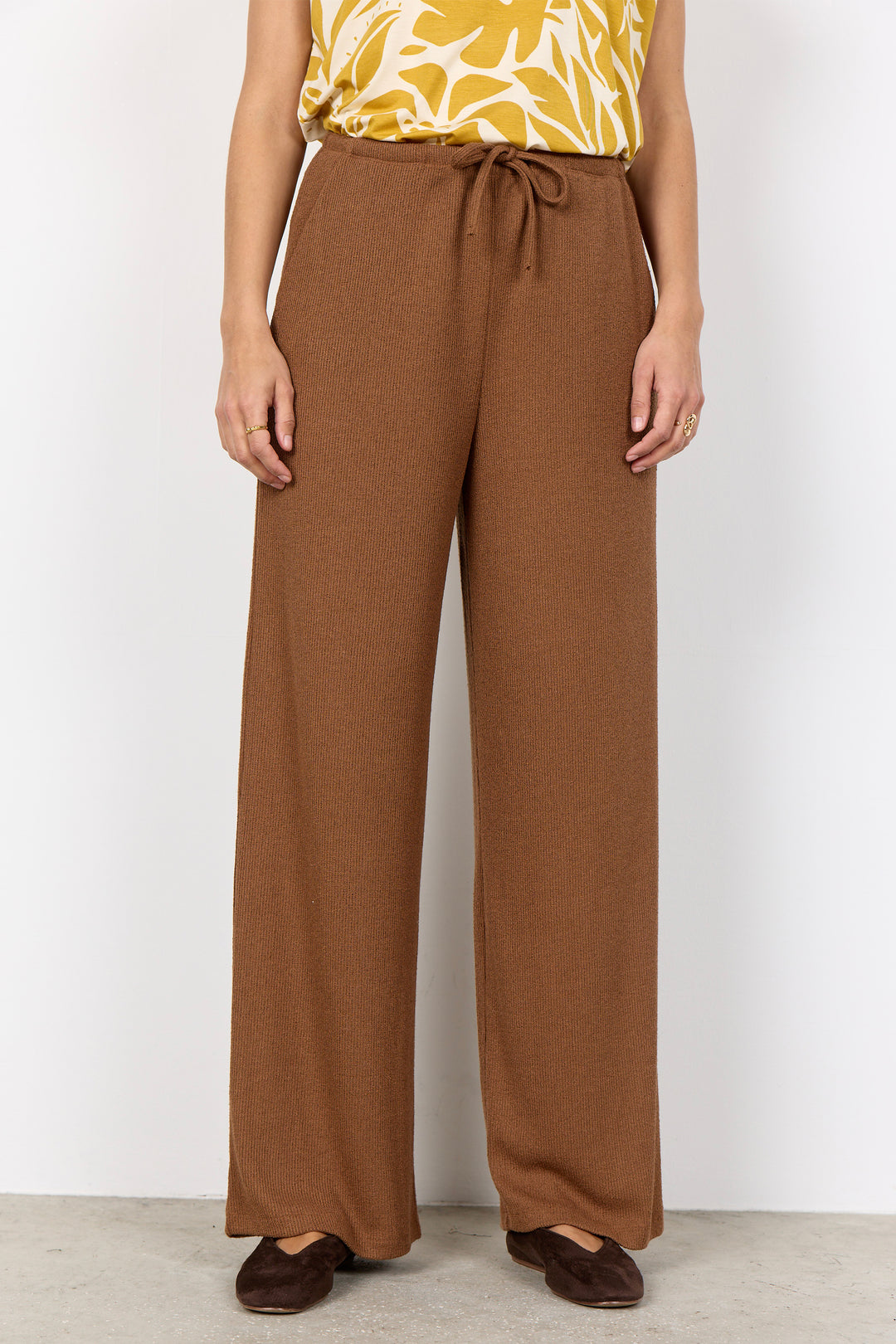 woman wearing light brown pants with a drawstring waist on a white background