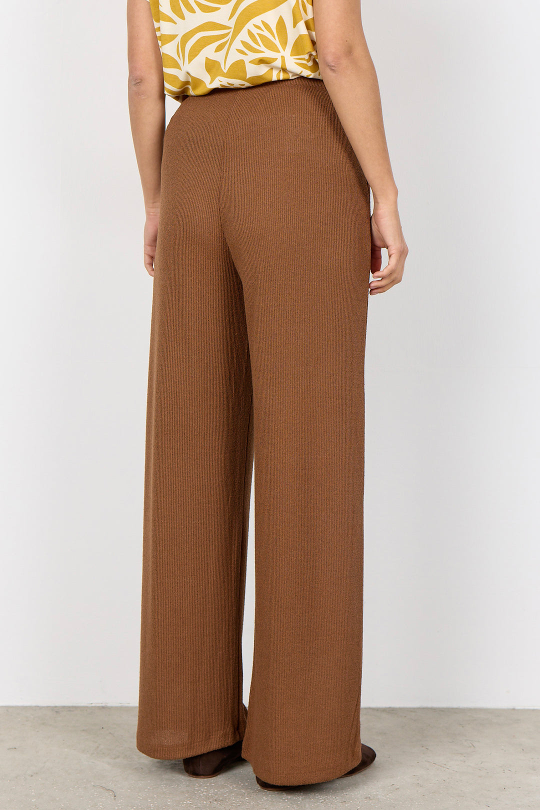 woman wearing light brown pants with a drawstring waist on a white background
