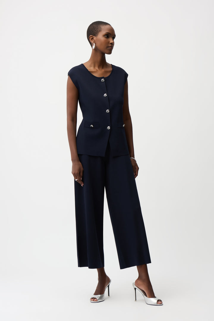 A model wearing a dark navy blue sleeveless button-front top and matching wide-leg cropped pants, styled with silver high-heeled sandals against a plain white studio background.