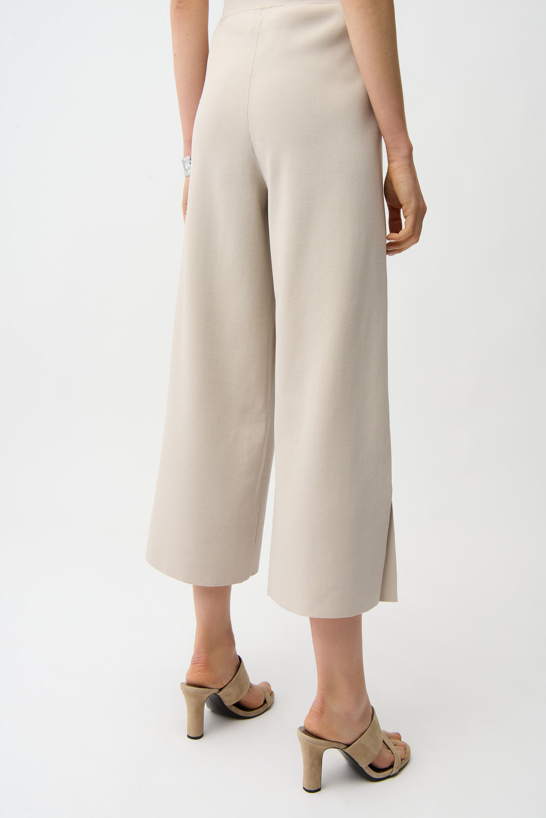 Person wearing beige wide-leg pants on a white background