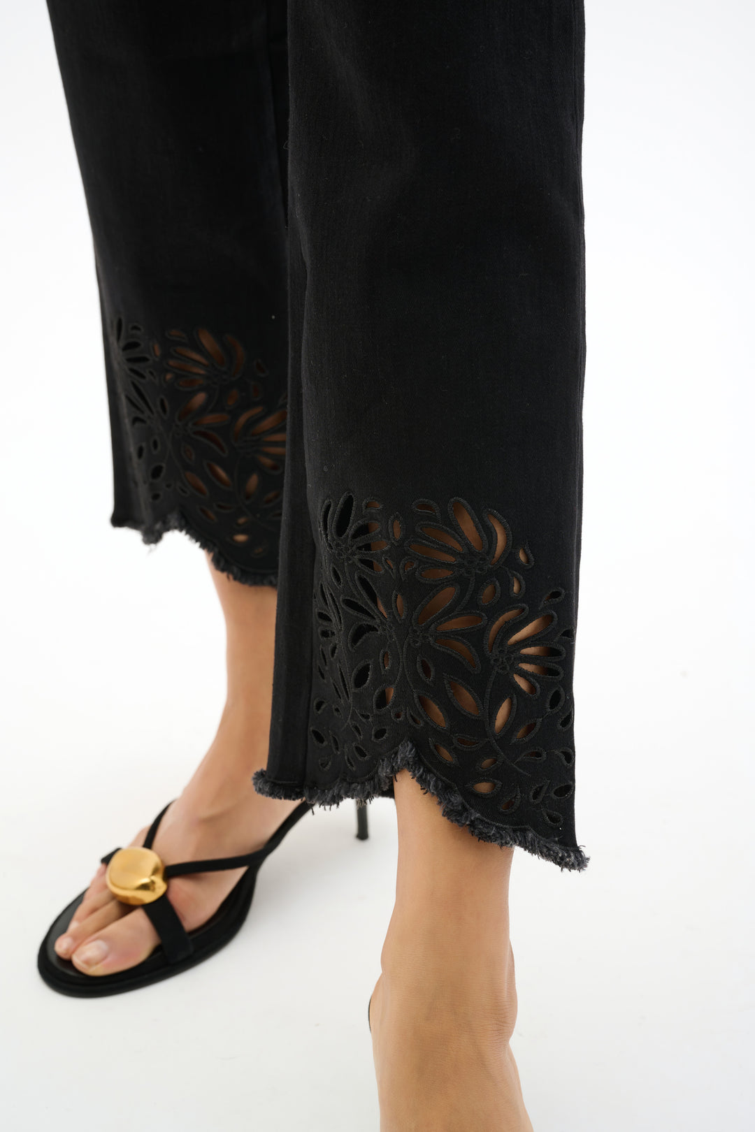 Black pants with laser cut detailing on a white background