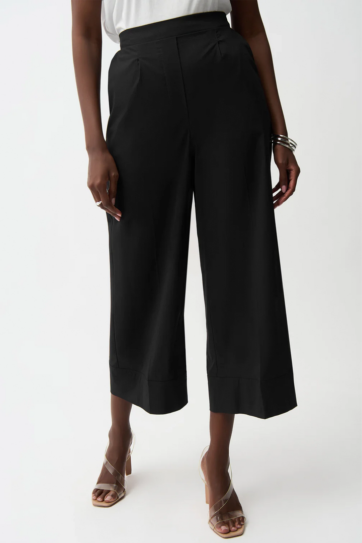 Person wearing black wide-leg pants on a white background