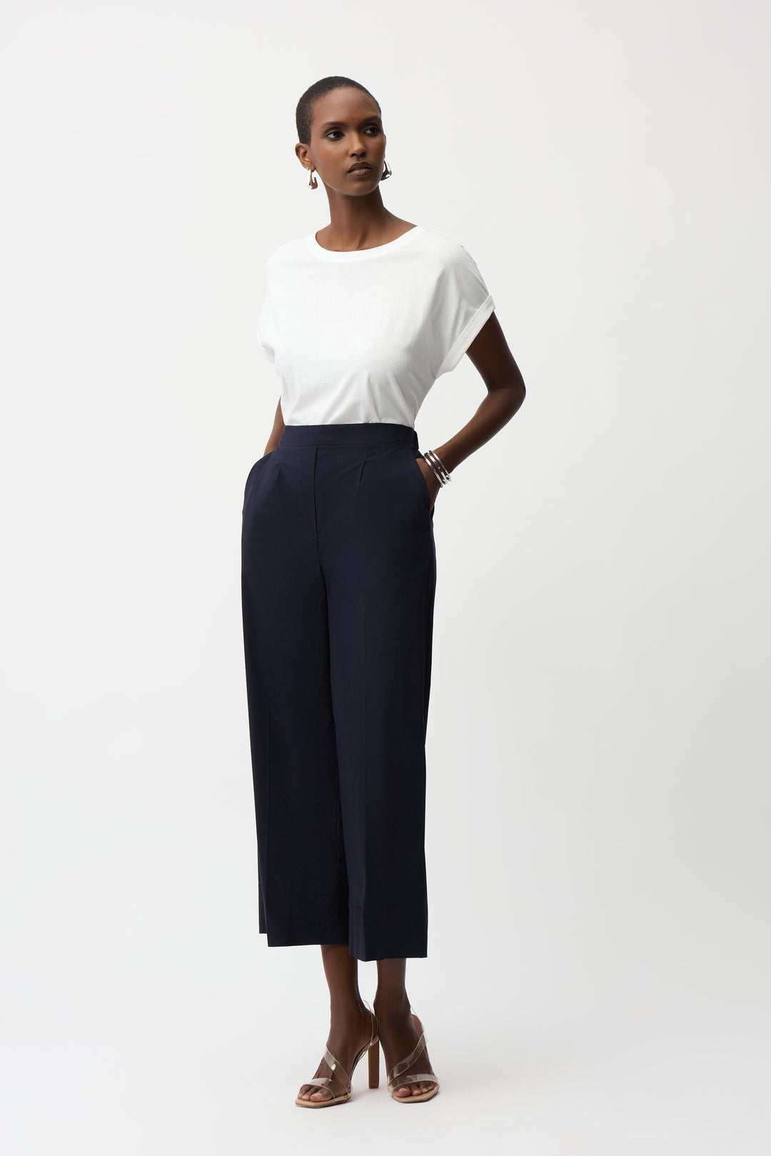 Woman wearing a white top and navy pants on a white background