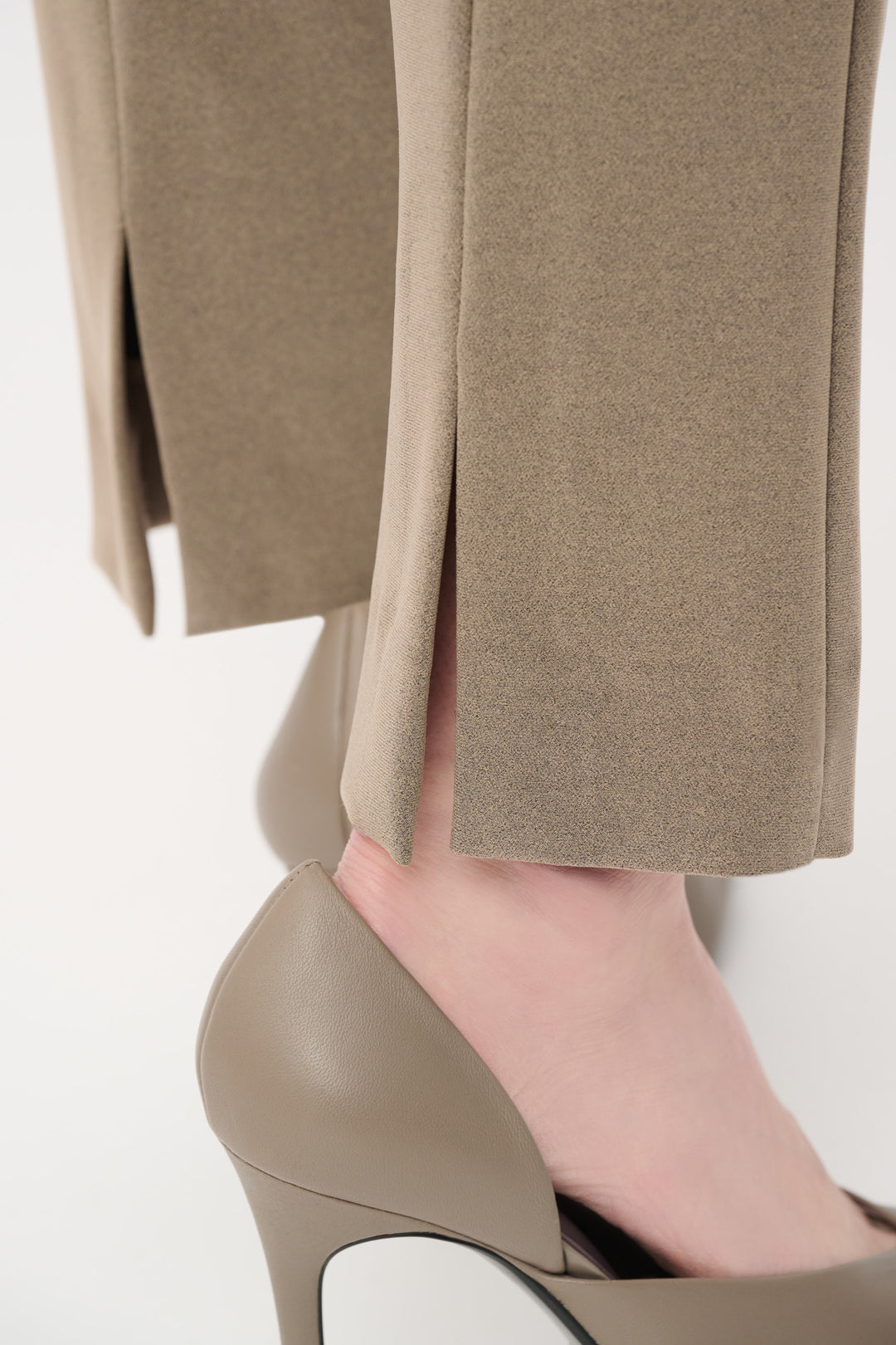 Close-up of beige pants and high-heeled shoes on a white background