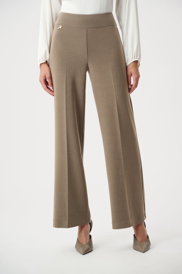 Beige wide-leg pants worn with a white blouse on a white background