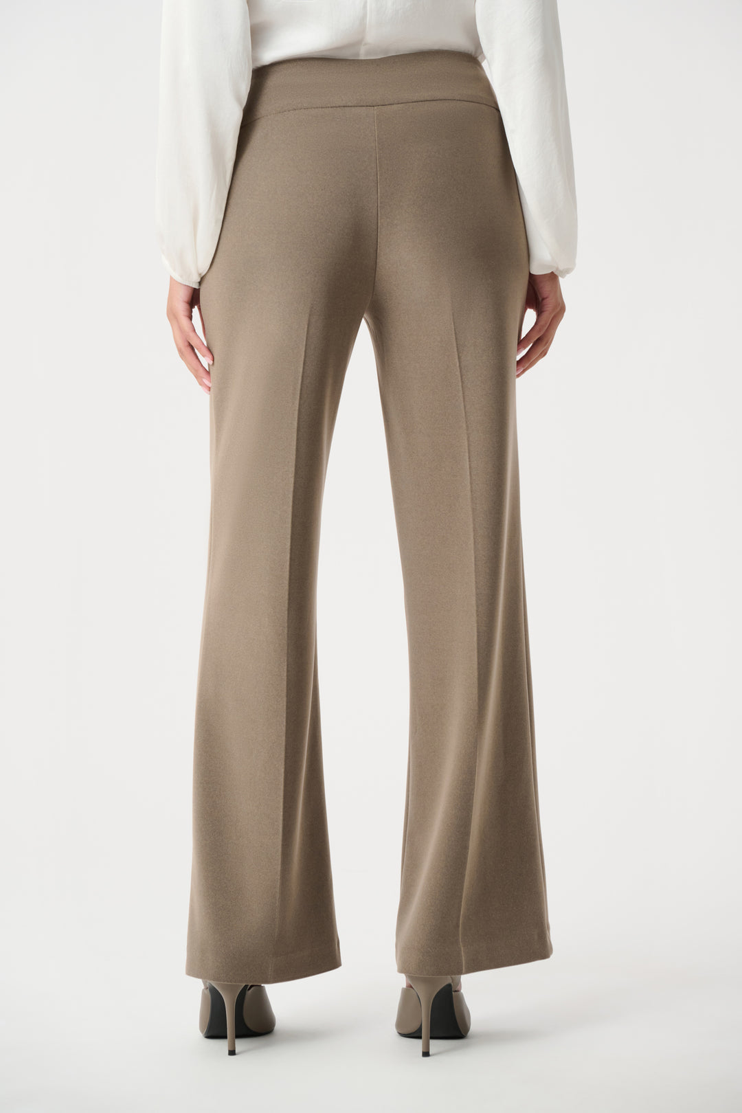 Beige wide-leg pants worn with a white blouse on a white background