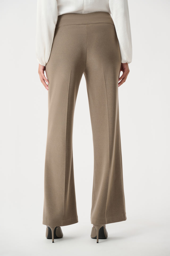 Beige wide-leg pants worn with a white blouse on a white background