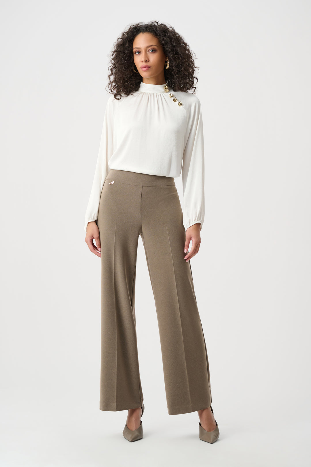 Woman wearing a white blouse and beige pants on a white background