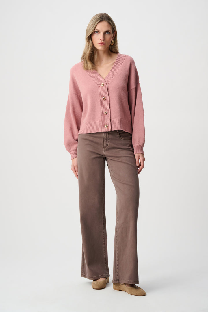 Woman wearing a pink cardigan and brown pants on a white background