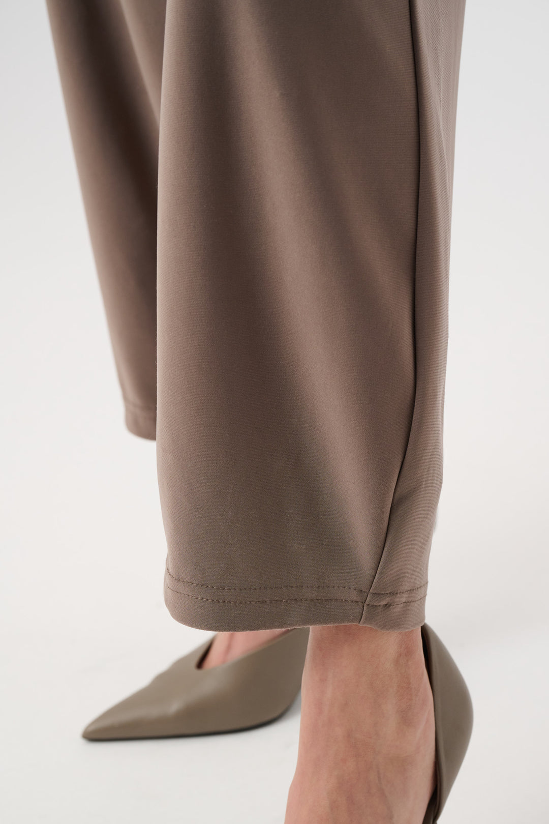 Close-up of brown pants and beige shoes on a white background