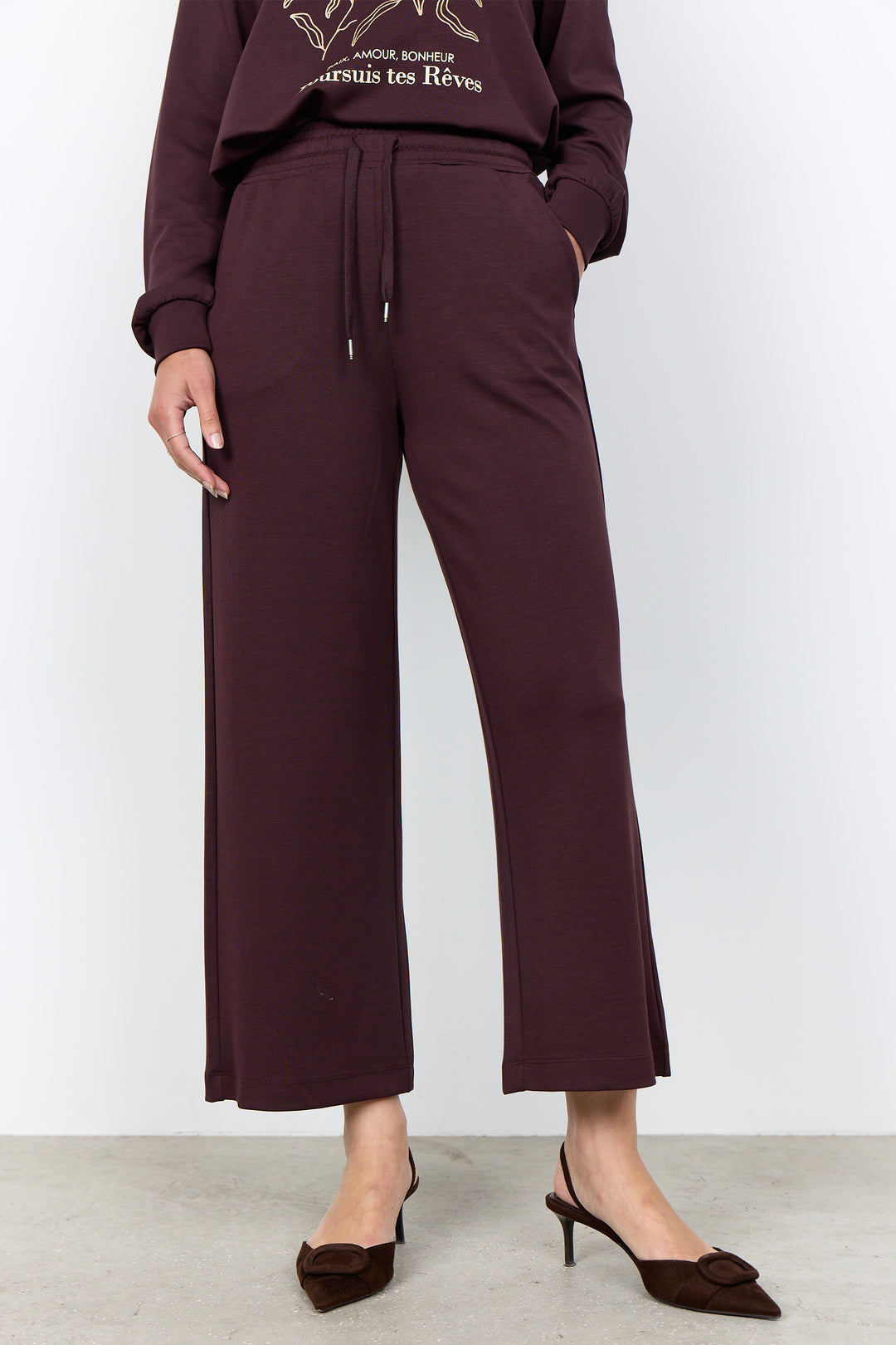 woman wearing casual straight leg sweatpants and matching sweater on a white background. 