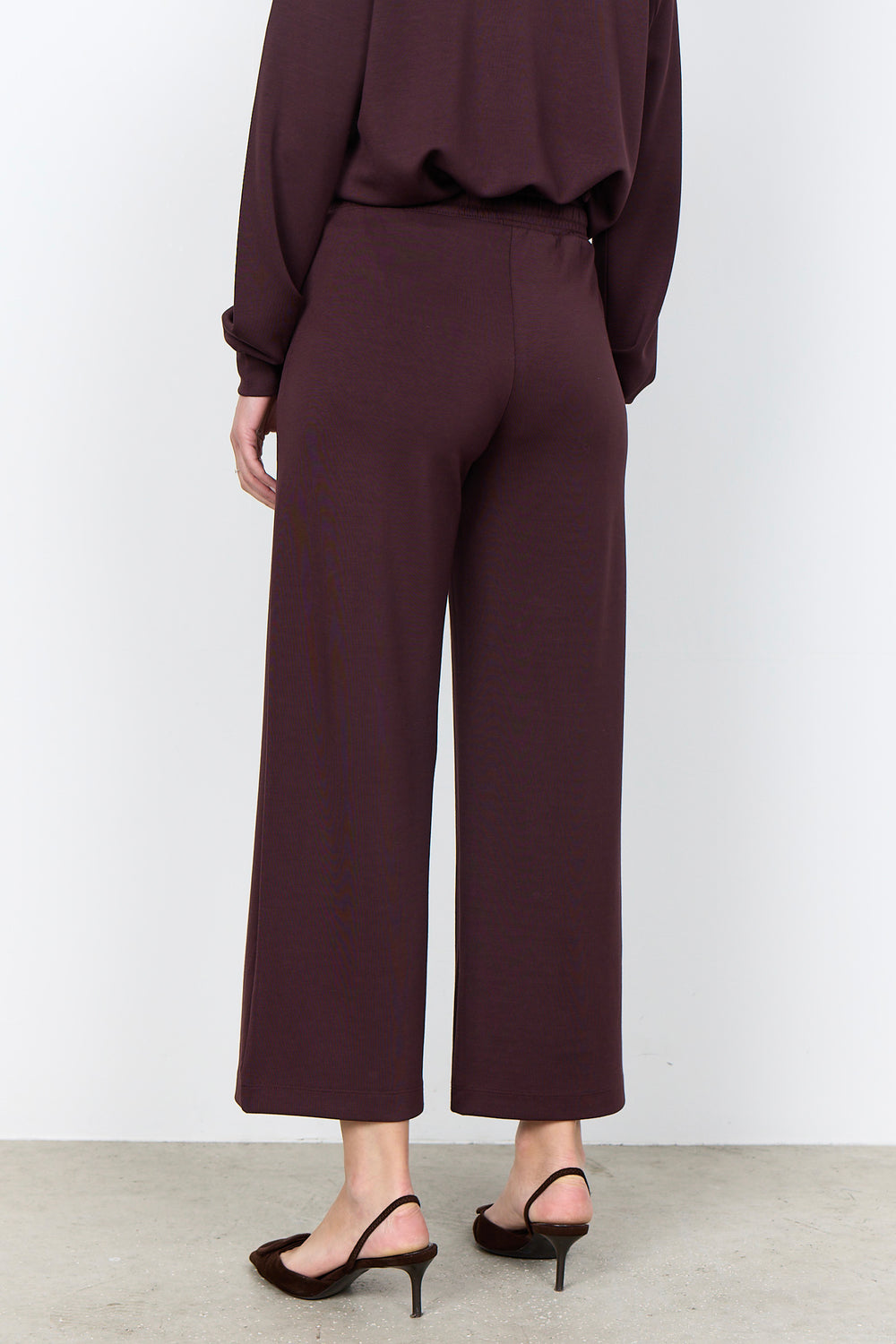 woman wearing casual straight leg sweatpants and matching sweater on a white background. 