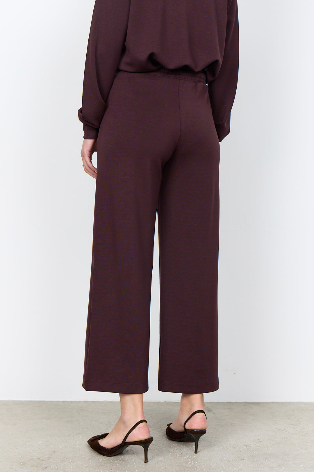 woman wearing casual straight leg sweatpants and matching sweater on a white background. 