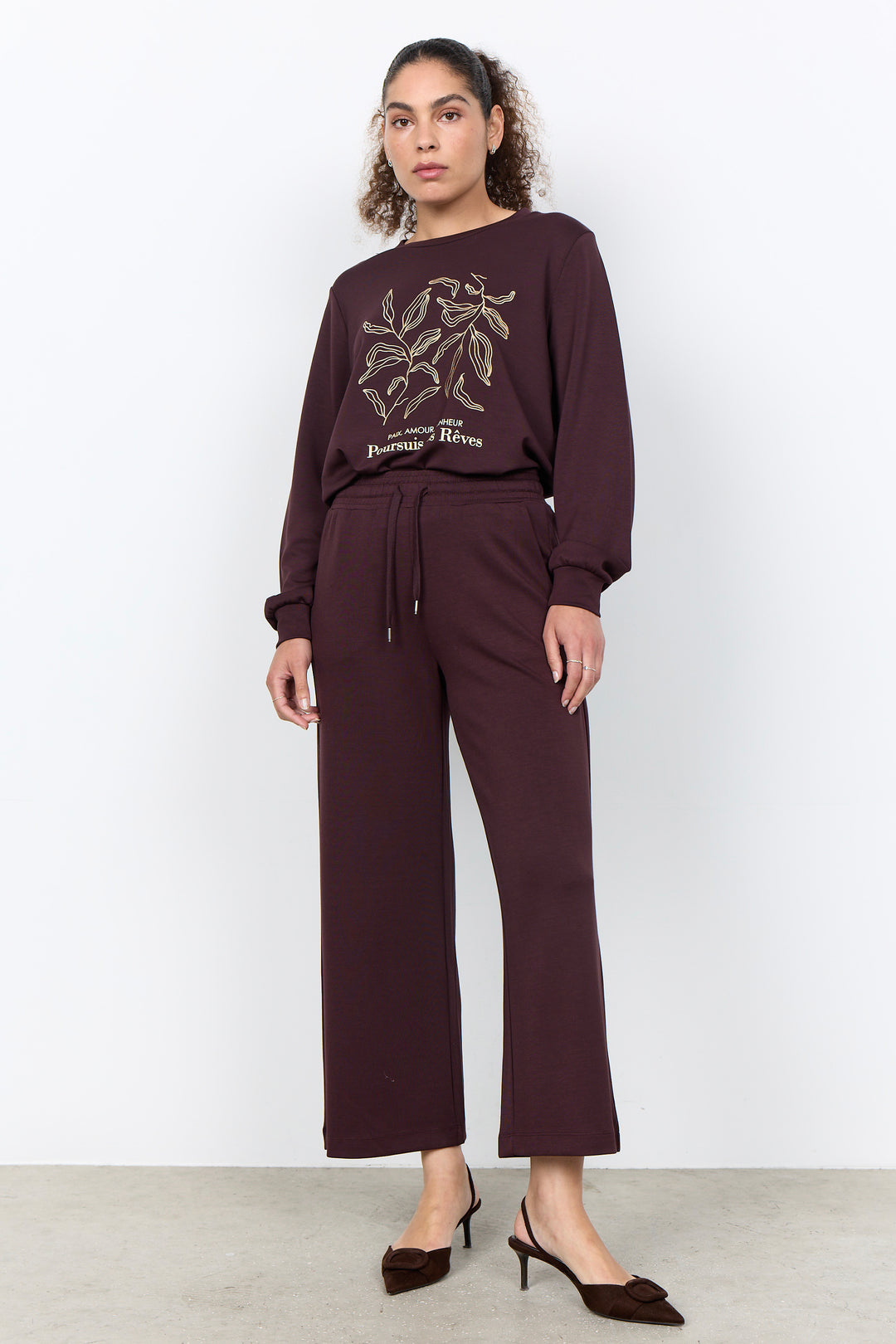 woman wearing casual straight leg sweatpants and matching sweater on a white background. 
