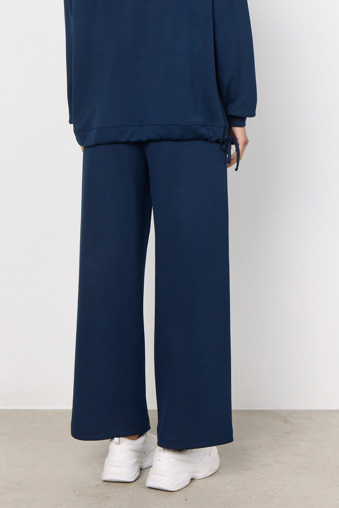 woman wearing casual straight leg sweatpants and matching sweater on a white background. 
