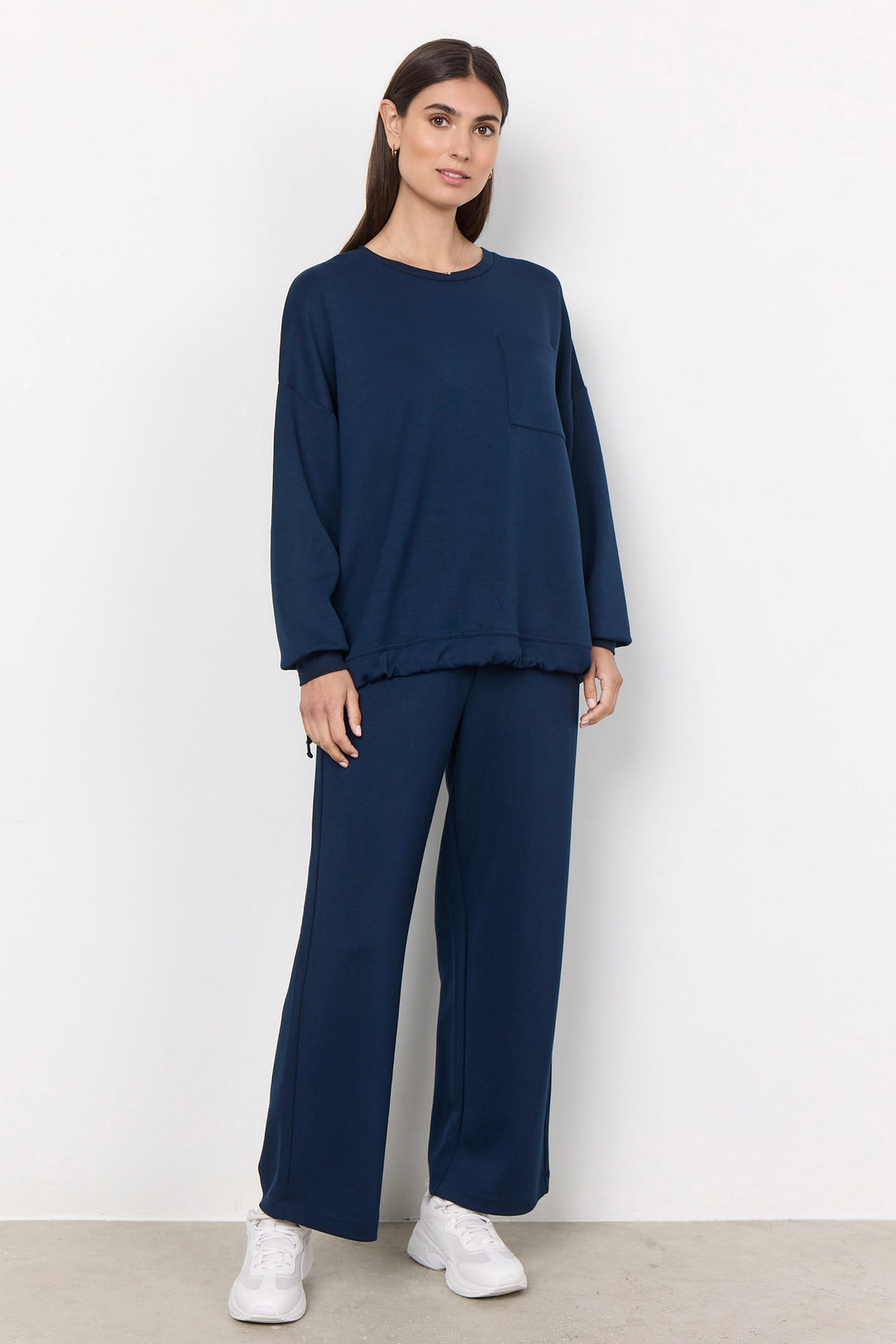 woman wearing casual straight leg sweatpants and matching sweater on a white background. 