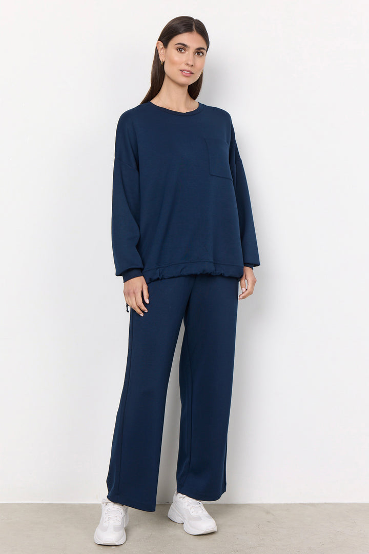 woman wearing casual straight leg sweatpants and matching sweater on a white background. 