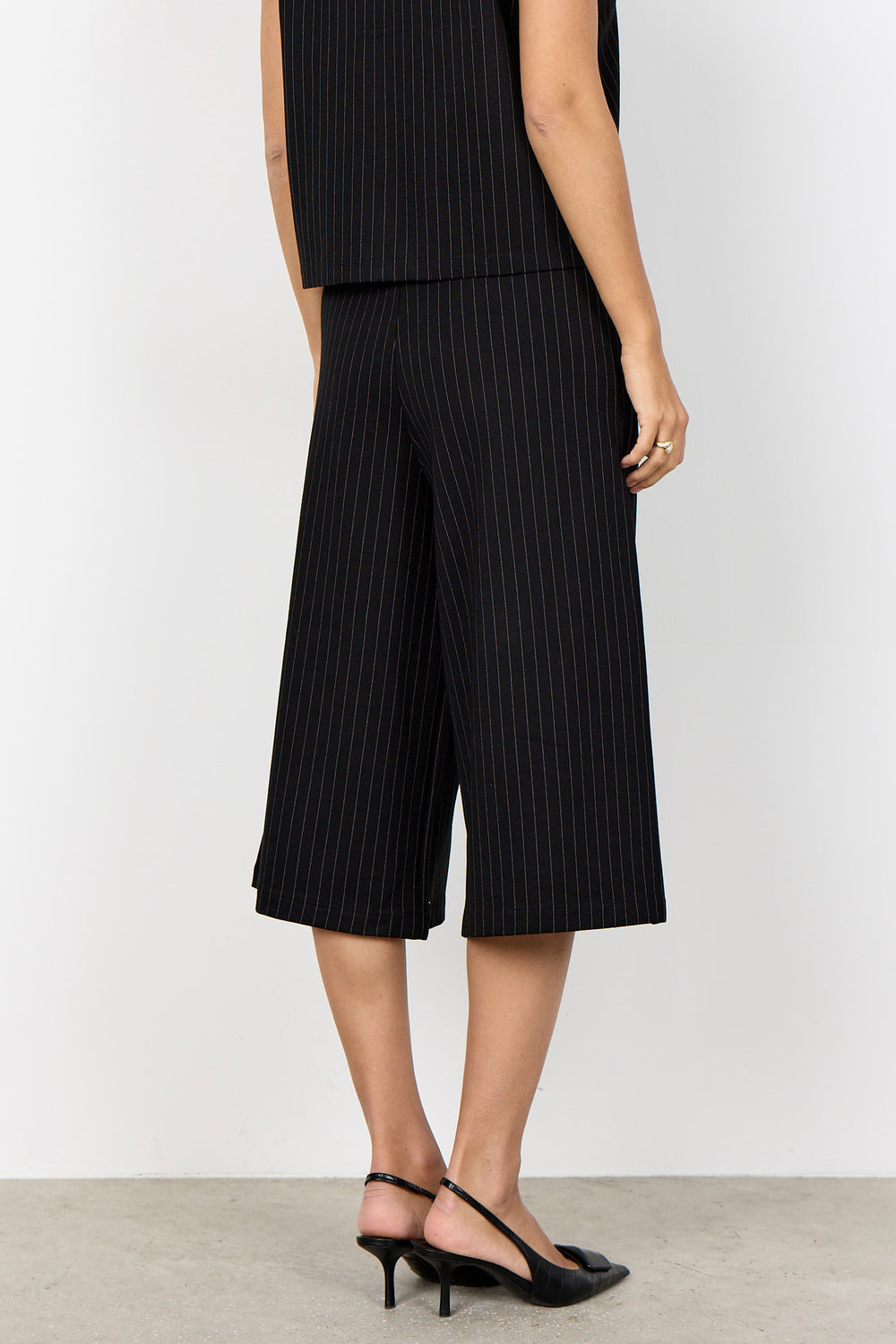 woman wearing wide leg pinstripe culottes and matching vest on a white background. 