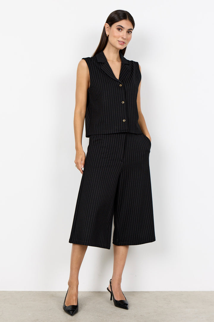 woman wearing wide leg pinstripe culottes and matching vest on a white background. 