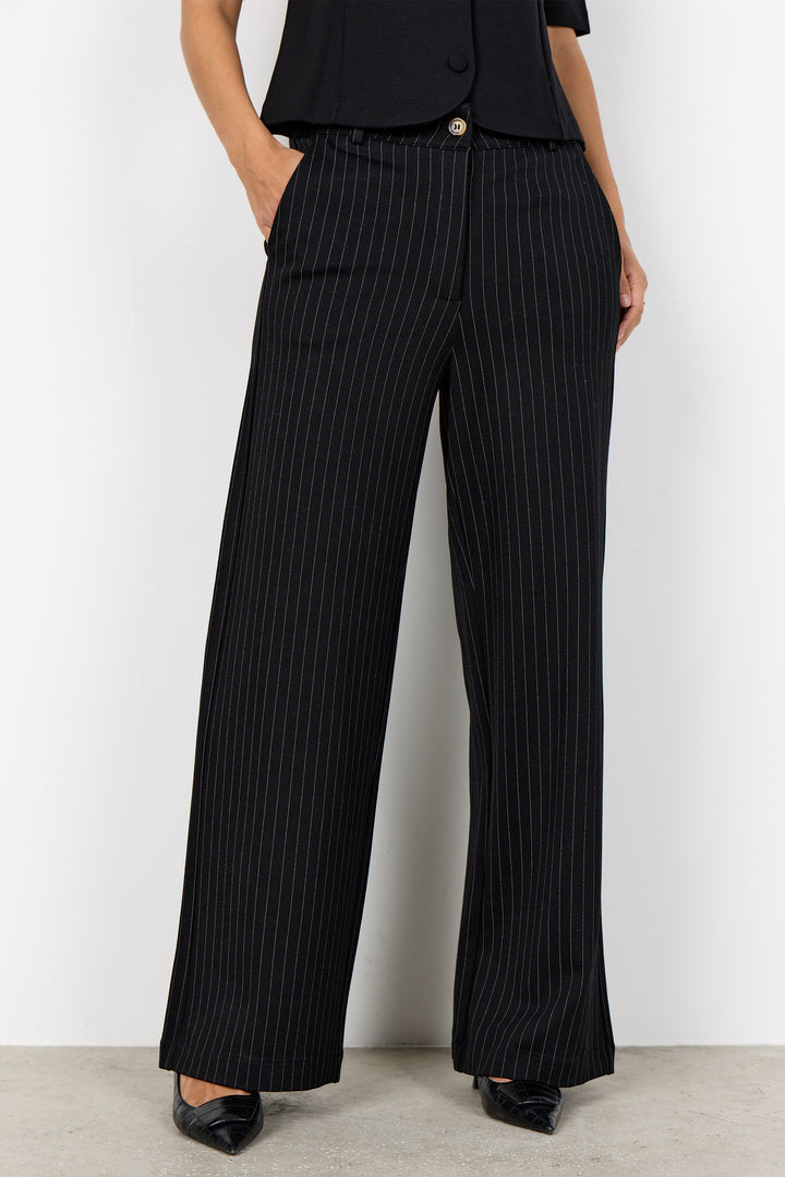 woman wearing a black blouse and black pinstripe wide leg pants on a white background. 