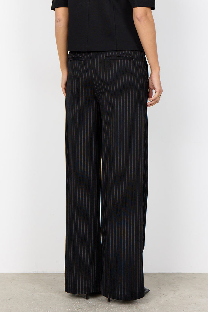 woman wearing a black blouse and black pinstripe wide leg pants on a white background. 