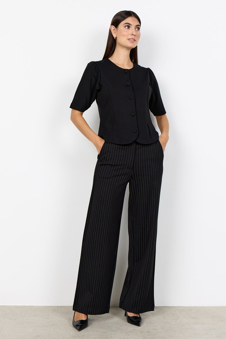woman wearing a black blouse and black pinstripe wide leg pants on a white background. 
