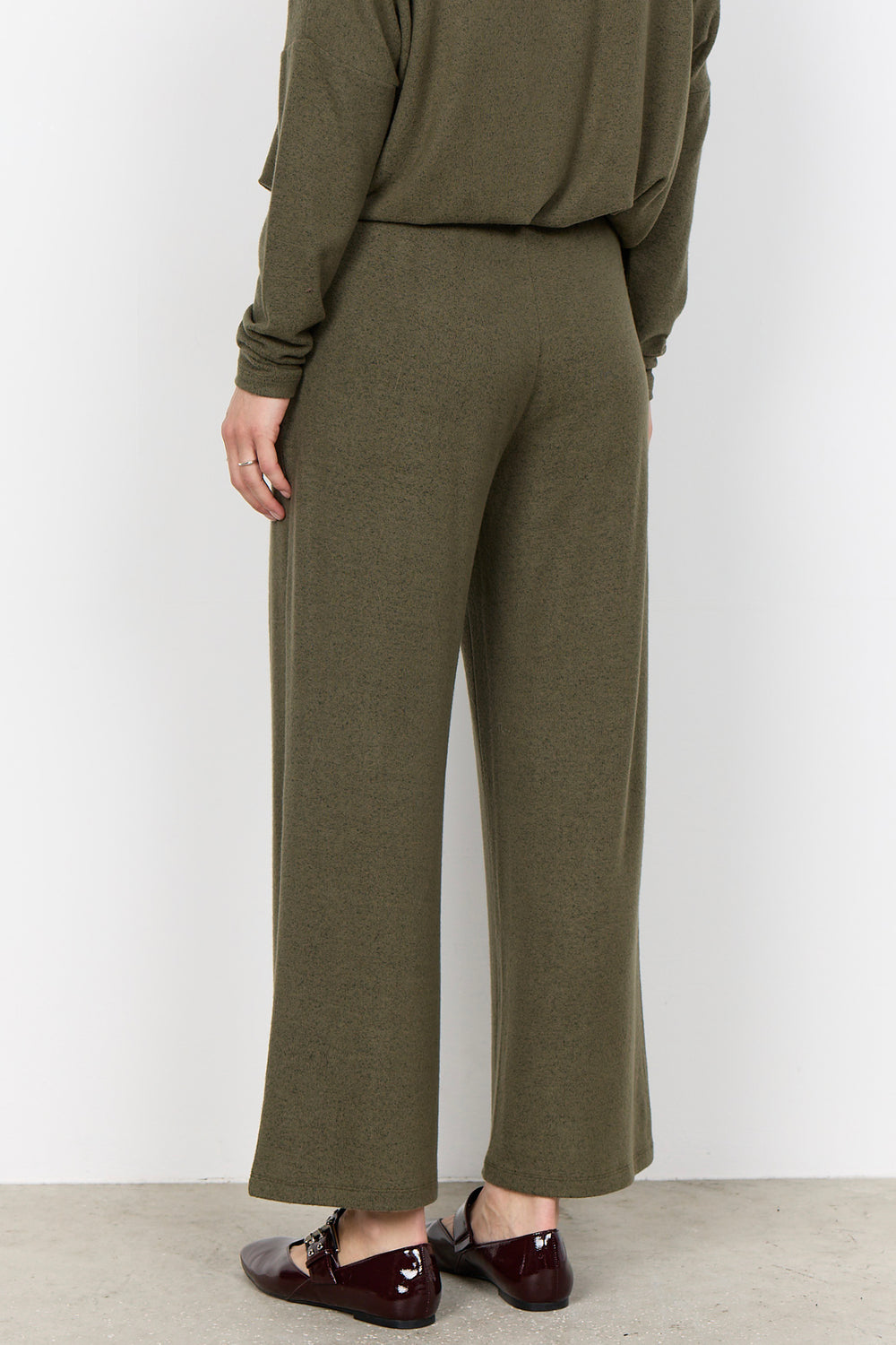 woman wearing casual sweatpants and matching top on a  white background. 