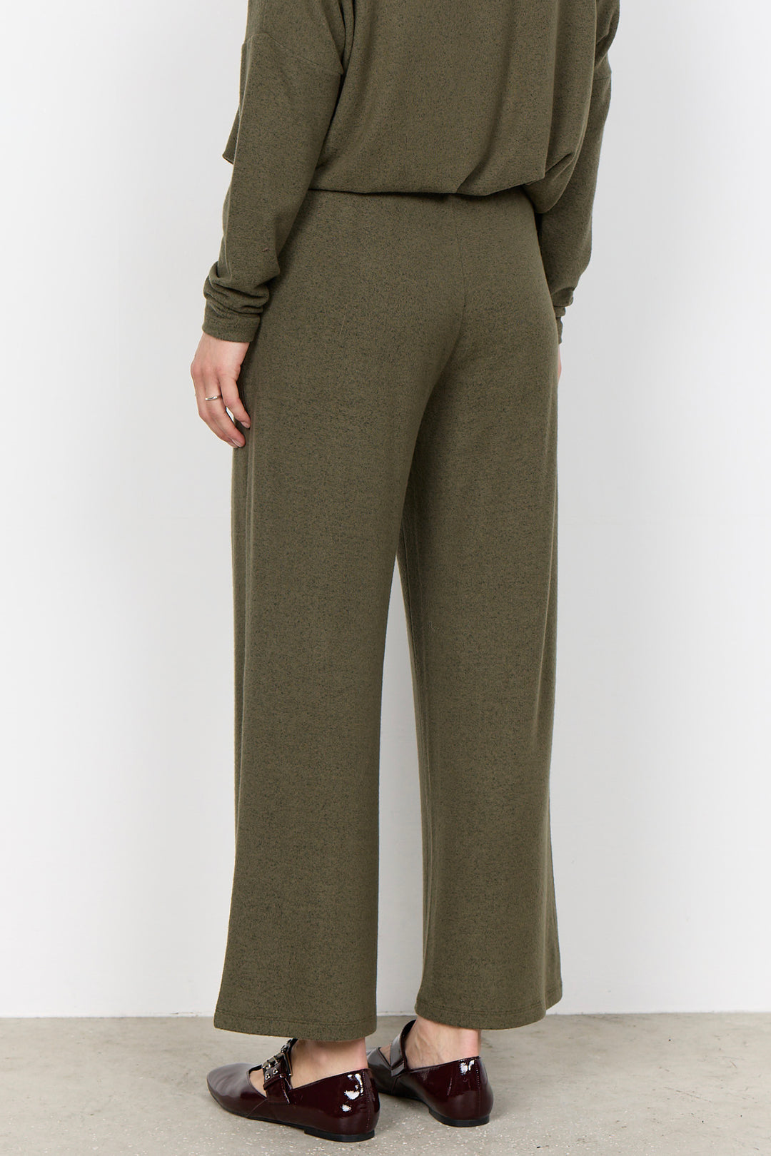 woman wearing casual sweatpants and matching top on a  white background. 
