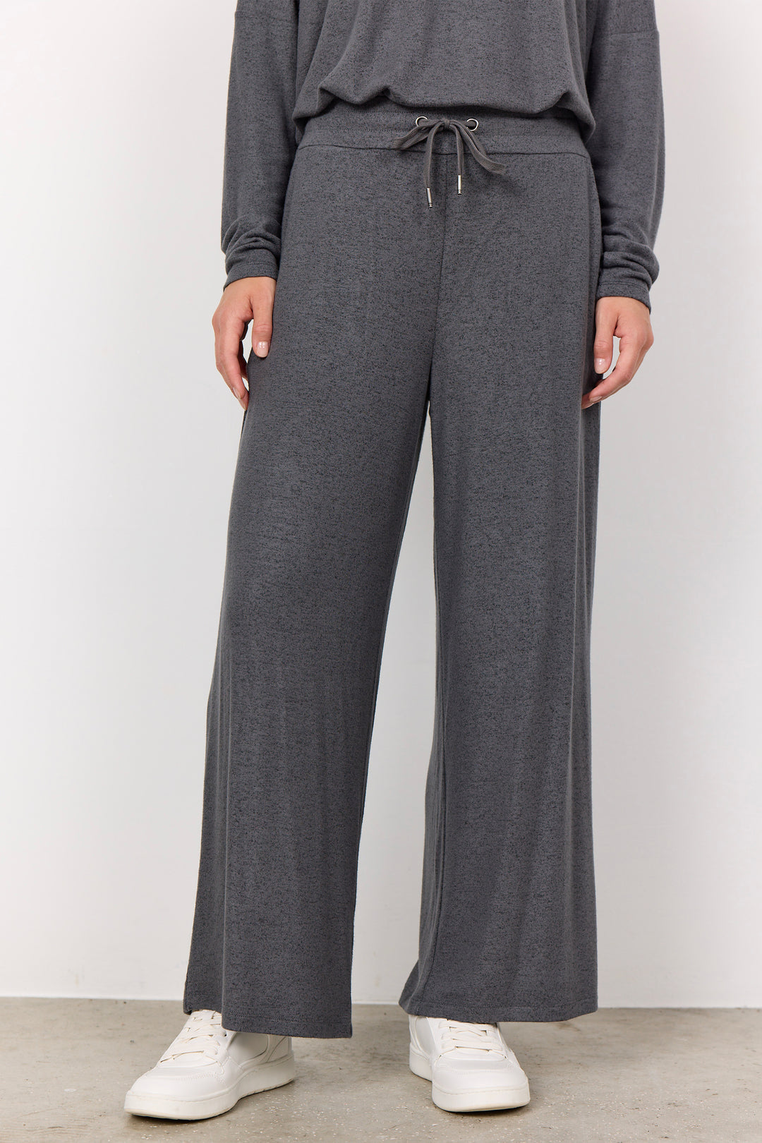 woman wearing casual sweatpants and matching top on a  white background. 