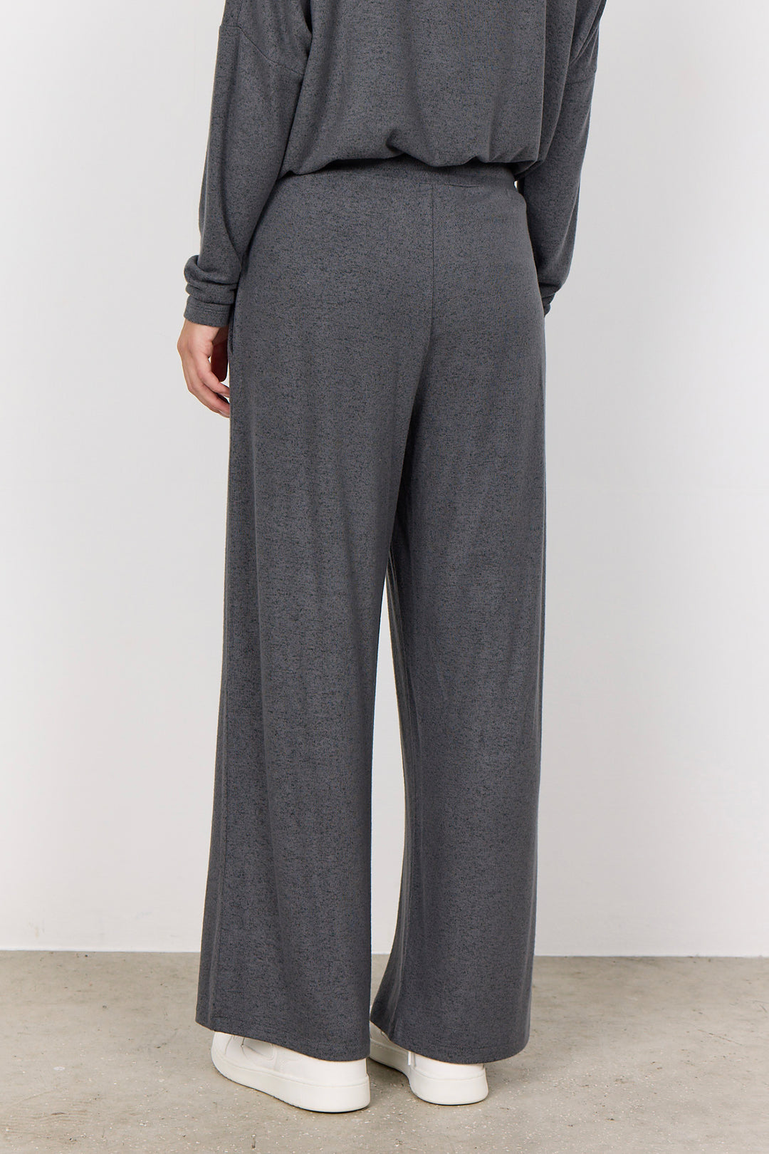 woman wearing casual sweatpants and matching top on a  white background. 