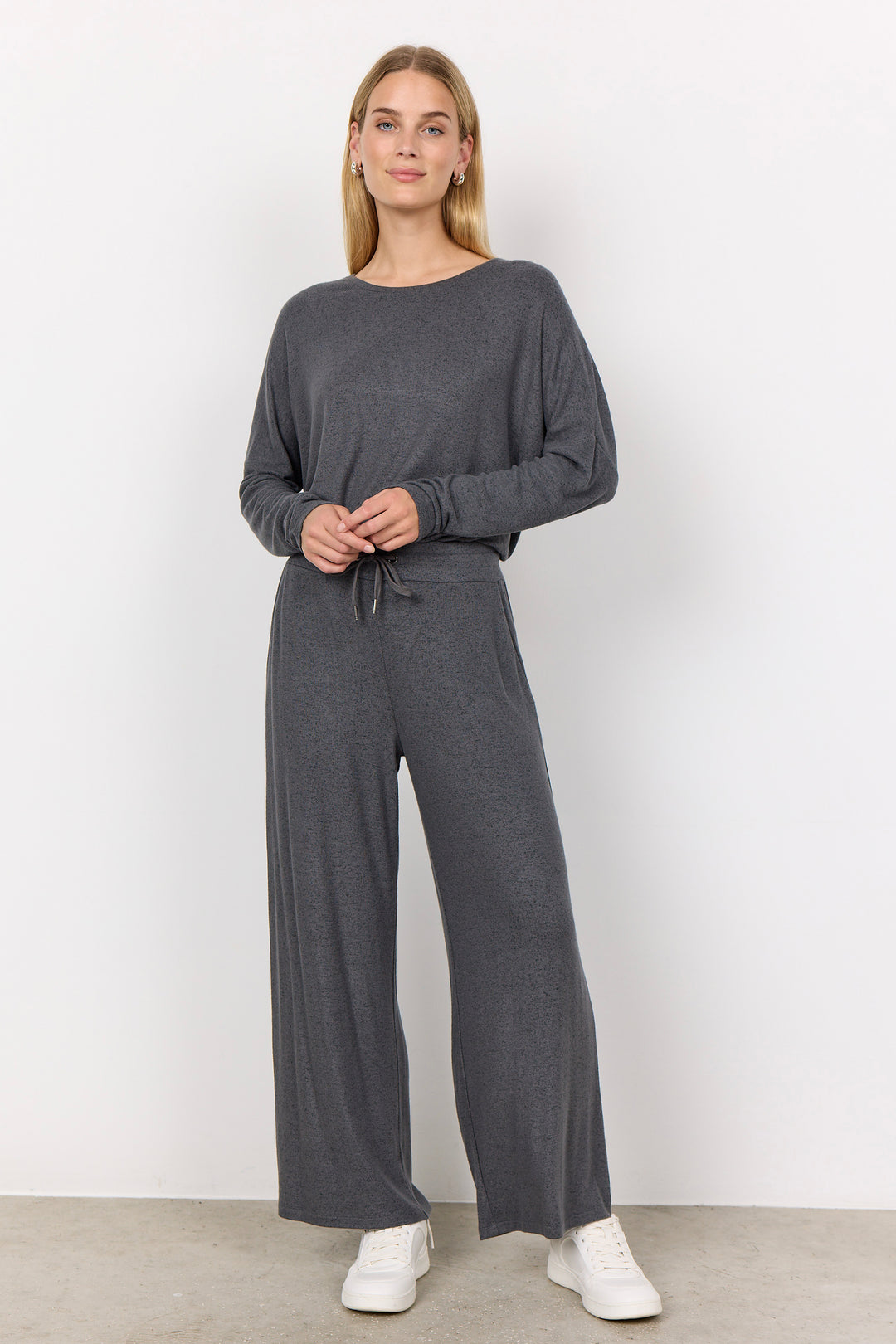 woman wearing casual sweatpants and matching top on a  white background. 