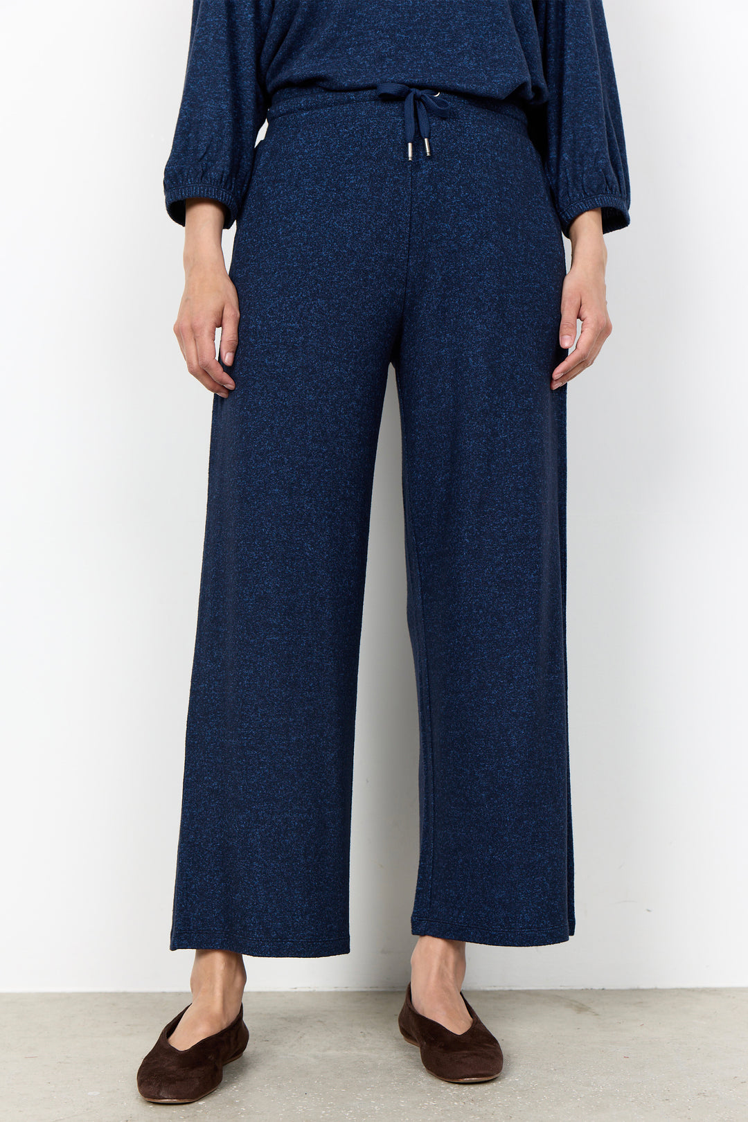 woman wearing casual sweatpants and matching top on a  white background. 