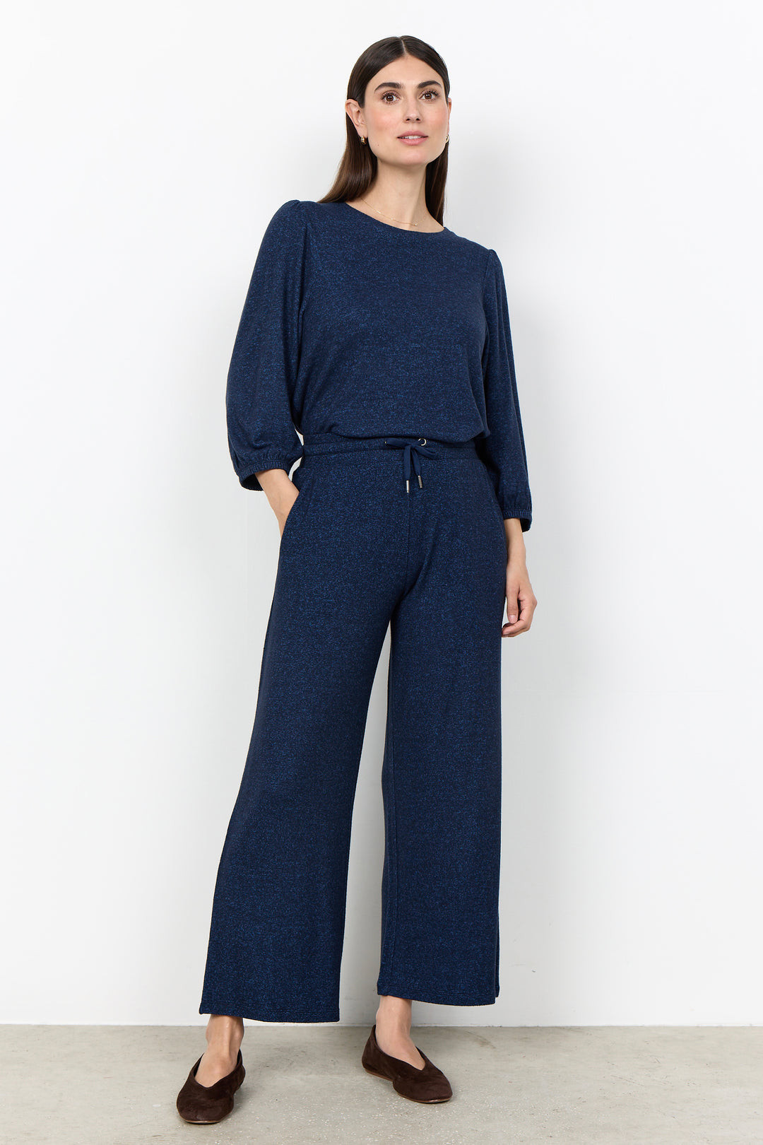 woman wearing casual sweatpants and matching top on a  white background. 