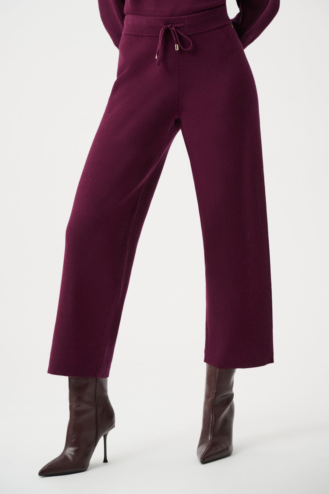 Purple outfit with high-waisted pants and brown boots on a white background