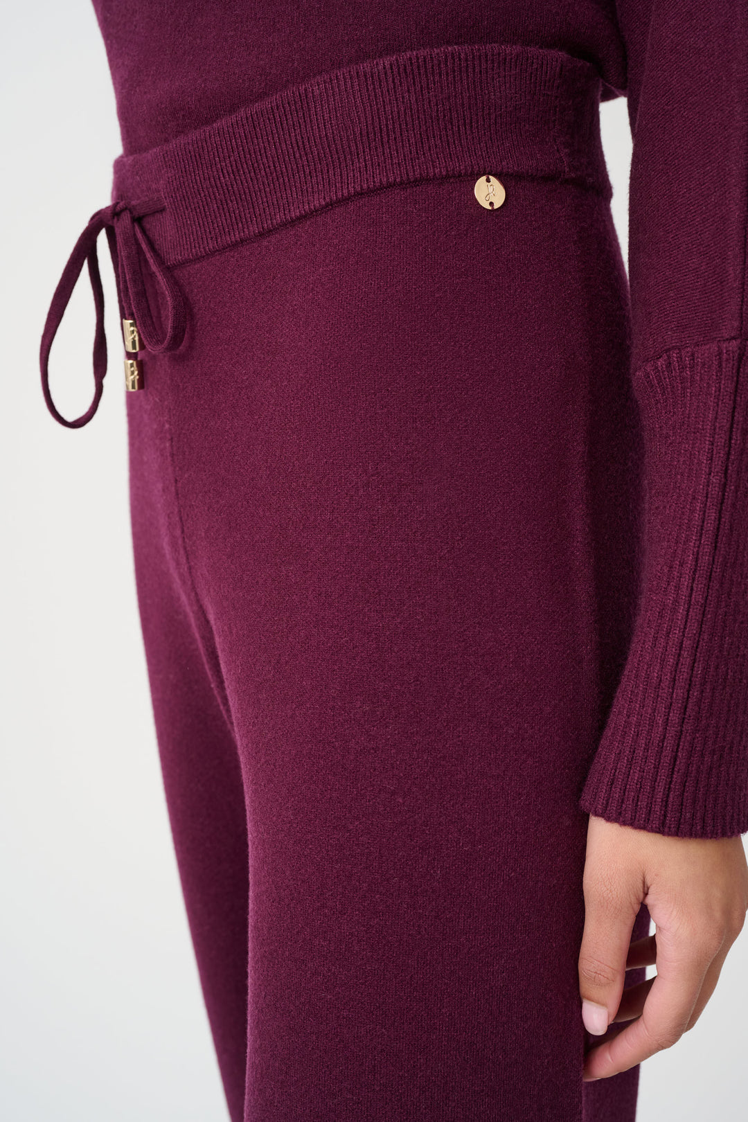 Close-up of a maroon knitted outfit with a drawstring and button on a white background