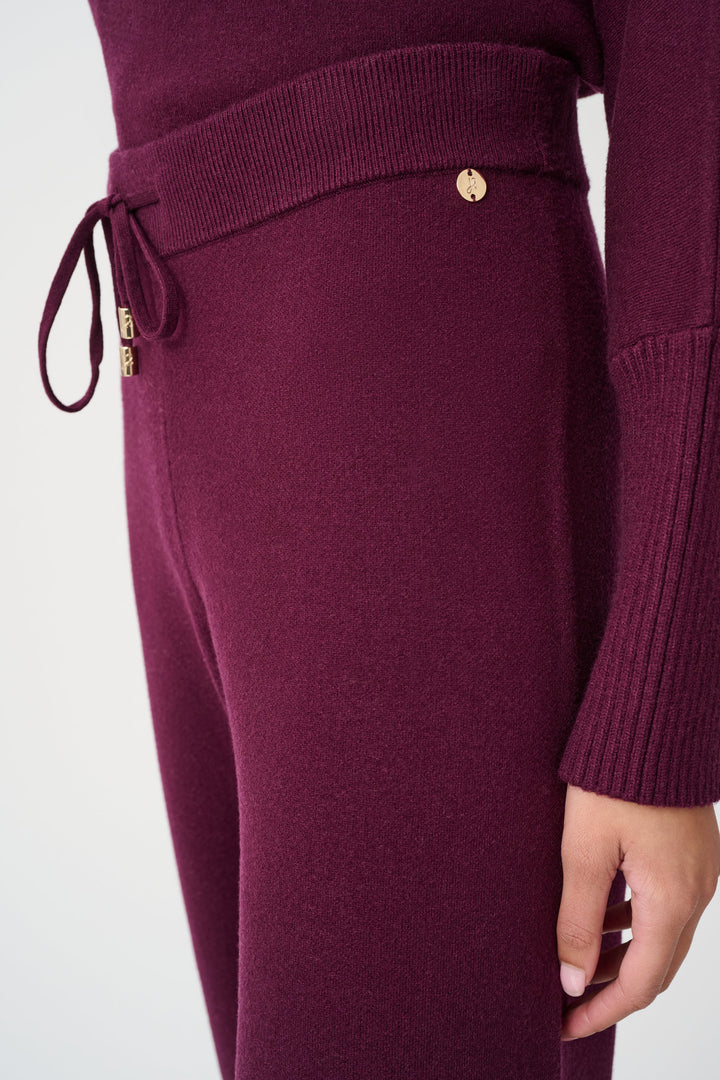 Close-up of a maroon knitted outfit with a drawstring and button on a white background