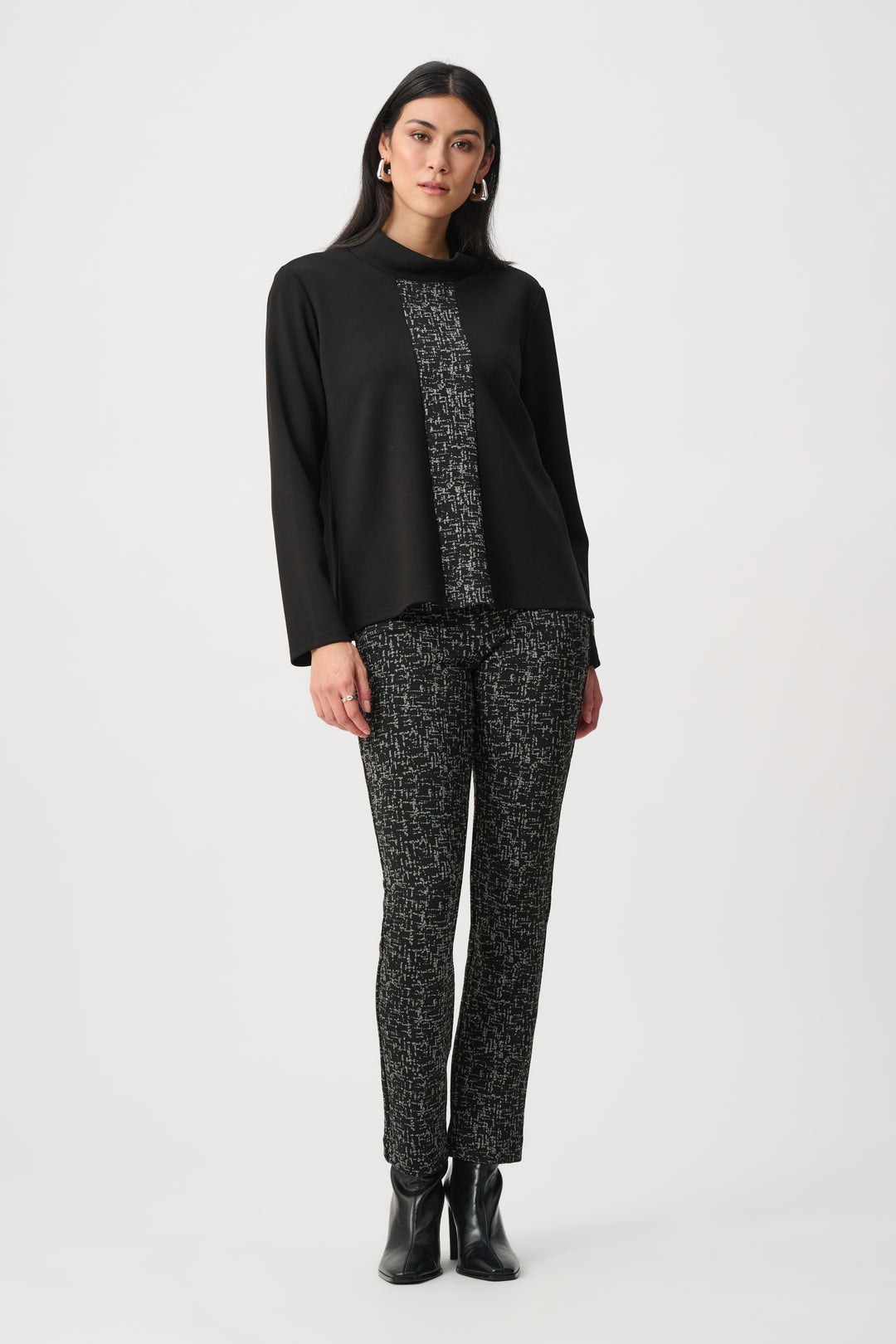 Woman wearing a black top with floral patterns and matching pants on a white background