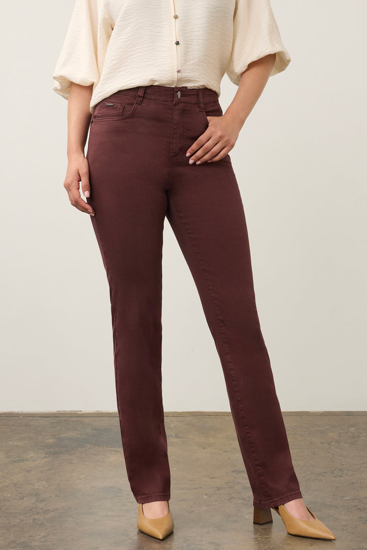 A model wearing high-waisted, straight-leg brown pants paired with a cream-colored blouse and beige heels, standing against a neutral studio background.