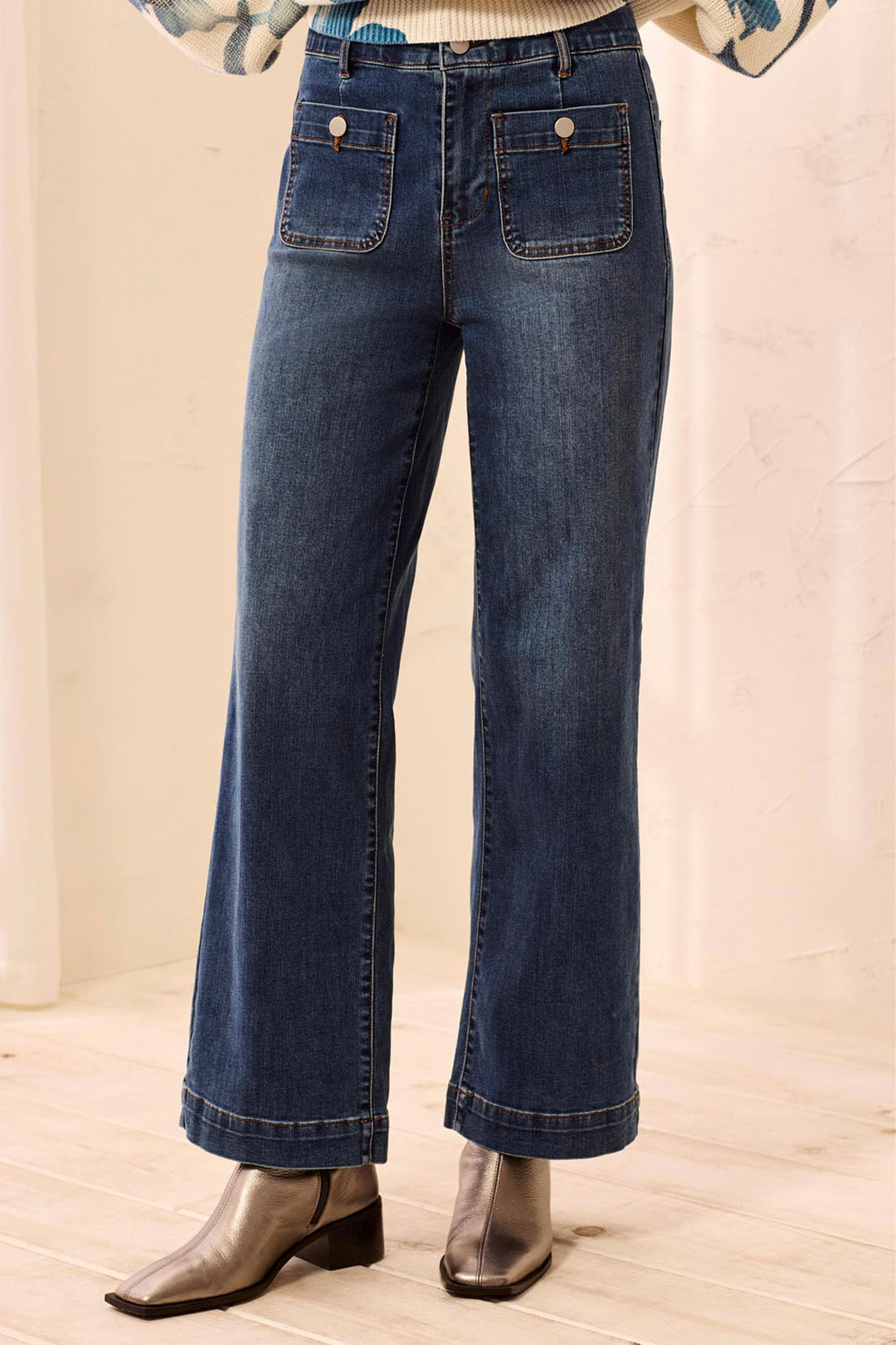 Blue jeans worn by a person on a beige background