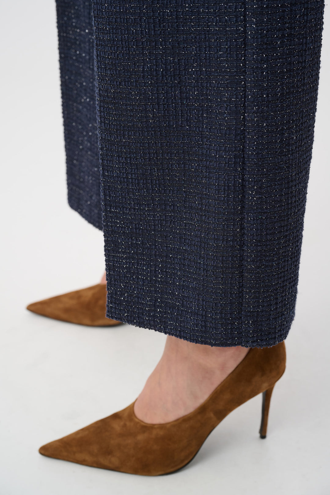 Navy textured pants with brown high-heeled shoes on a light gray background