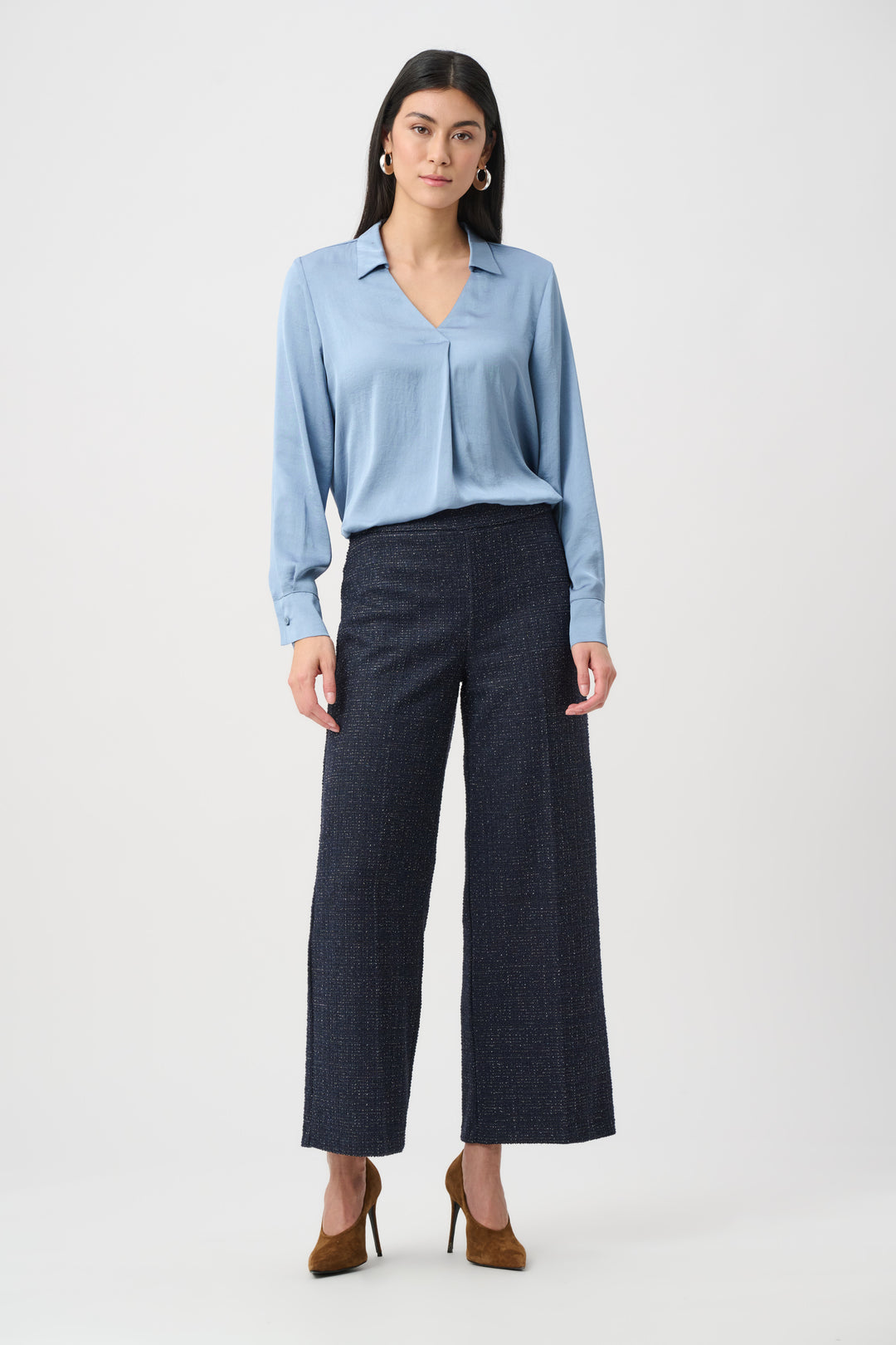 Woman wearing a light blue blouse and dark gray pants on a white background