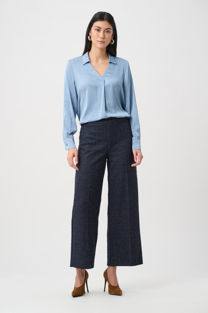 Woman wearing a light blue blouse and dark gray pants on a white background