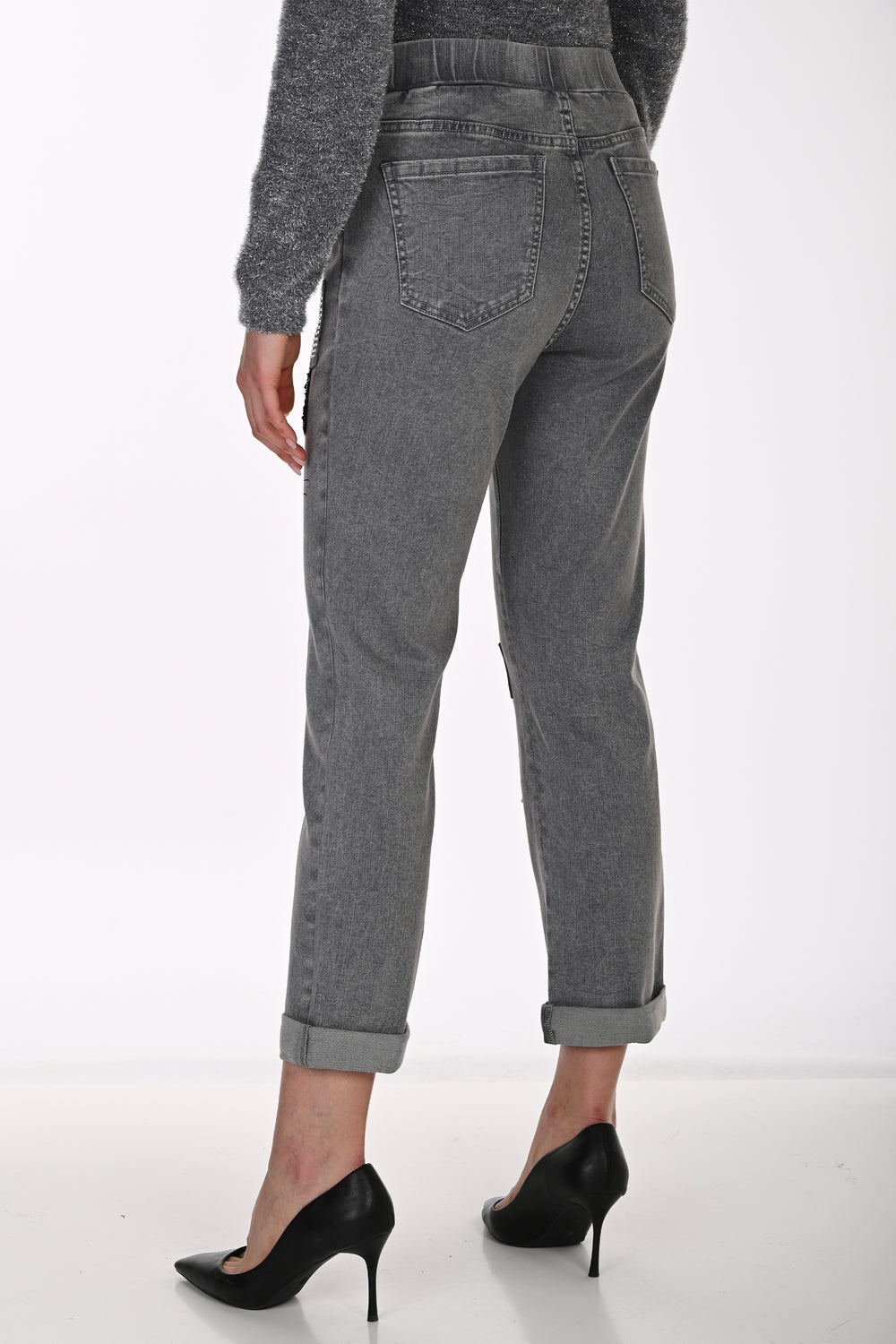 A person shown from the back wearing gray high-waisted cropped jeans with rolled cuffs and black pointed-toe heels against a clean white studio background.