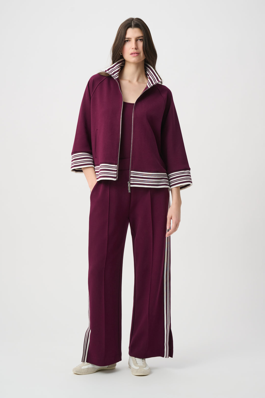 Woman wearing a maroon outfit with white stripes on a white background