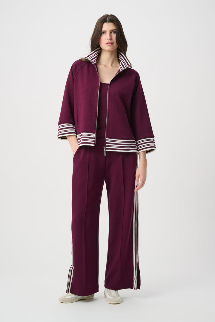 Woman wearing a maroon outfit with white stripes on a white background