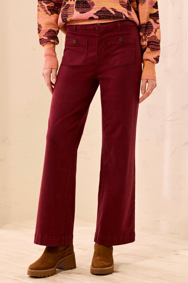 Person wearing burgundy pants and brown boots on a beige background