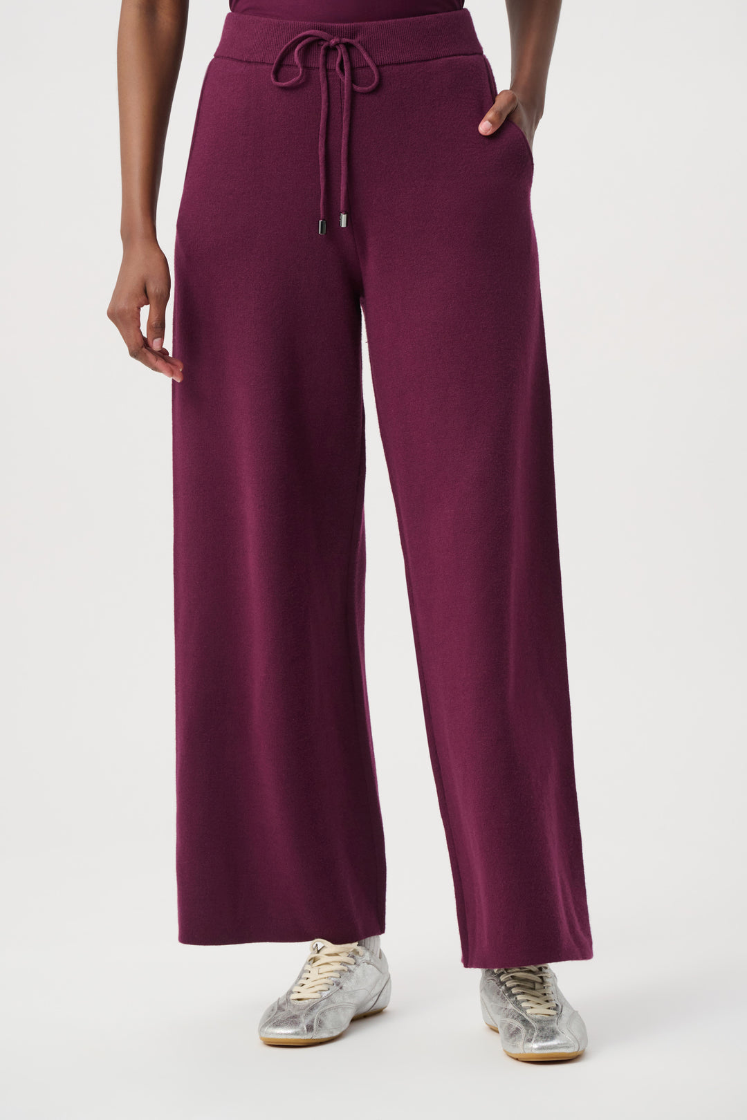 Woman wearing burgundy knit pants on a white background