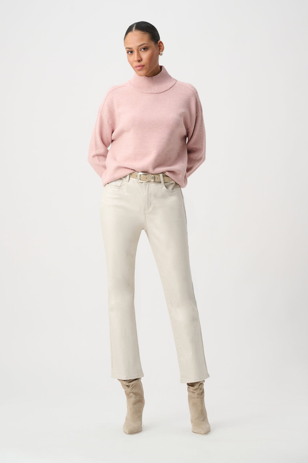 A woman modelling a white pair of metallic jeans with a pink sweater. 