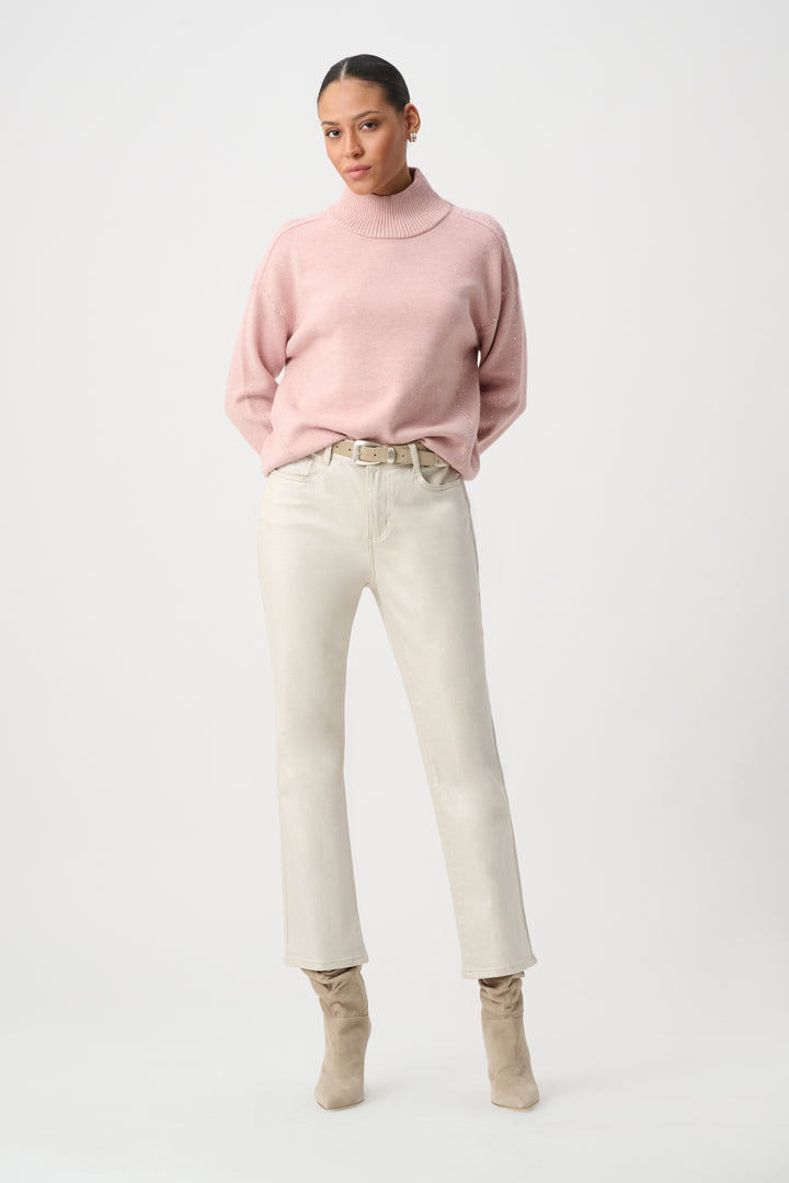 A woman modelling a white pair of metallic jeans with a pink sweater. 