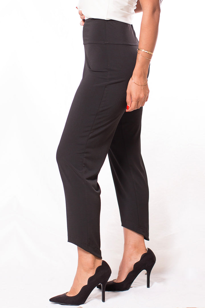 A woman modelling black pants with a high-low hem standing in front of a white background. 